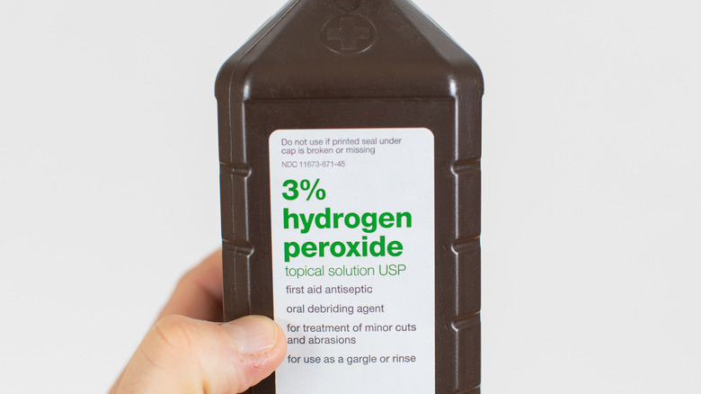 Hand holding a bottle of hydrogen peroxide 3%
