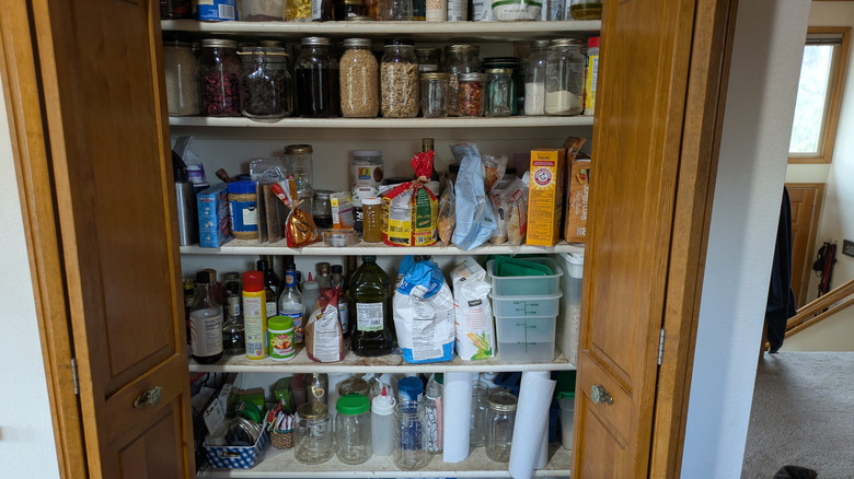A pantry is filled with bags, cans, and other containers.