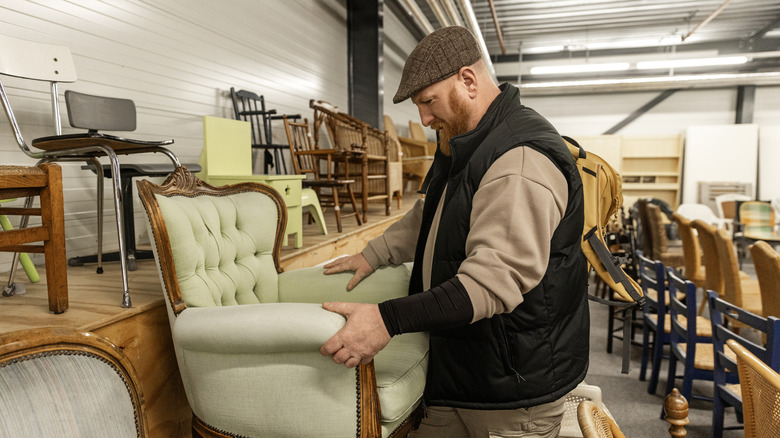 man looking at a piece of furniture at the thrift store