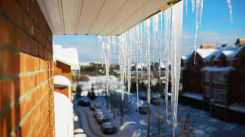 A side view of icicles hanging off a brick-sided home's gutter