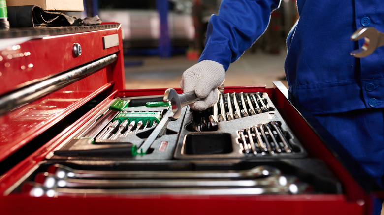 A mechanic selecting a wrench from a large tool box