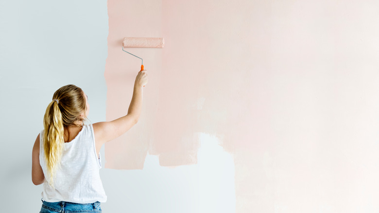 woman painting pink wall