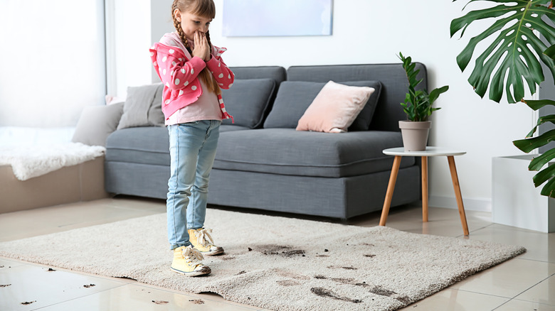 child standing over dirty carpet