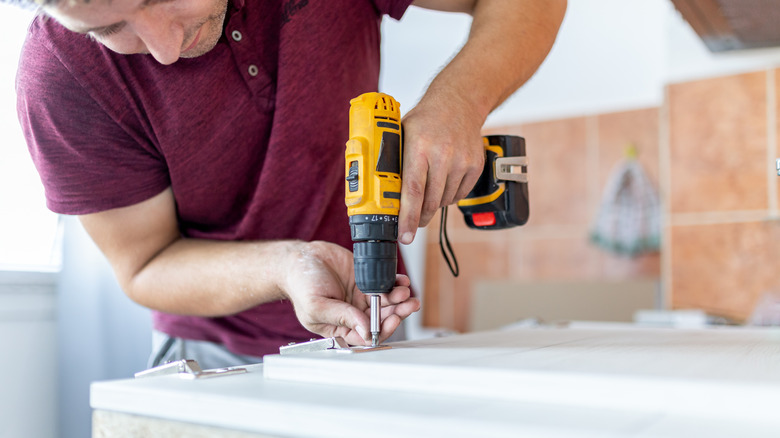 A person using a drill/driver to assemble furniture