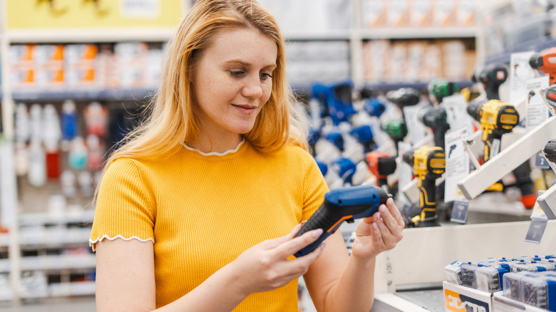 A woman holding an electric screwdriver in a store