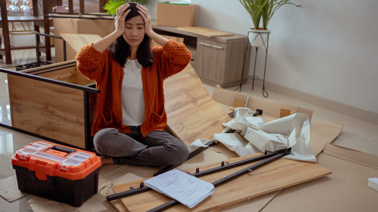Frustrated woman assembling furniture