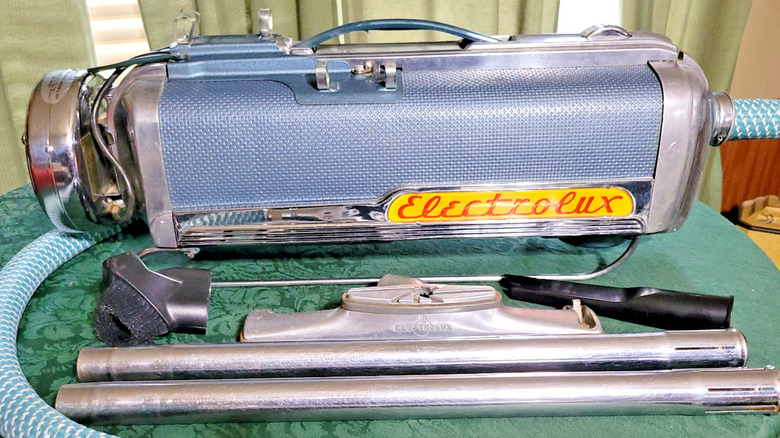 A vintage light blue and chrome canister vacuum (Electrolux Model LX) with accessories