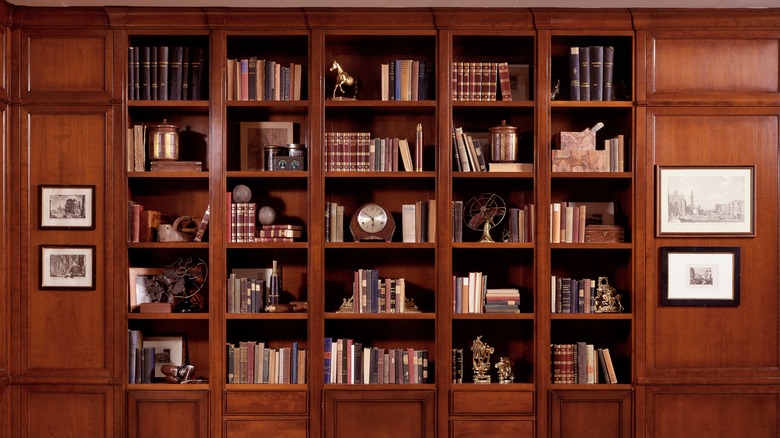 A walnut brown bookcase filled with books and ornaments.