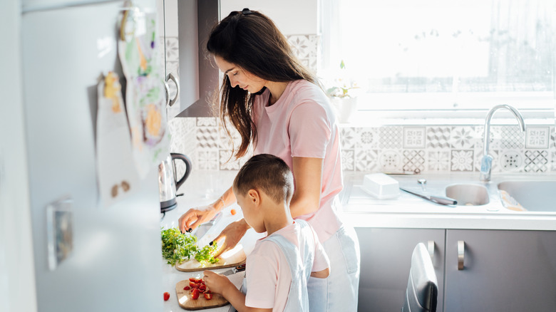 Mum teaching toddler child to cook.