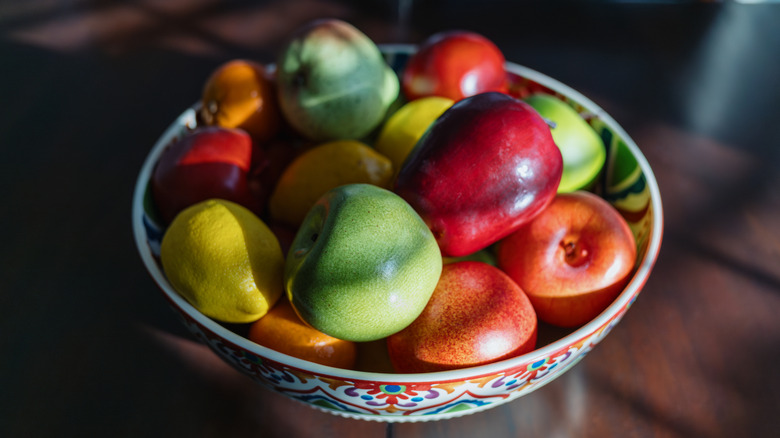 A fruit bowl full of apples of different colors and hues.