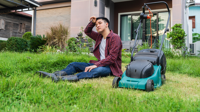 tired man next to lawnmower