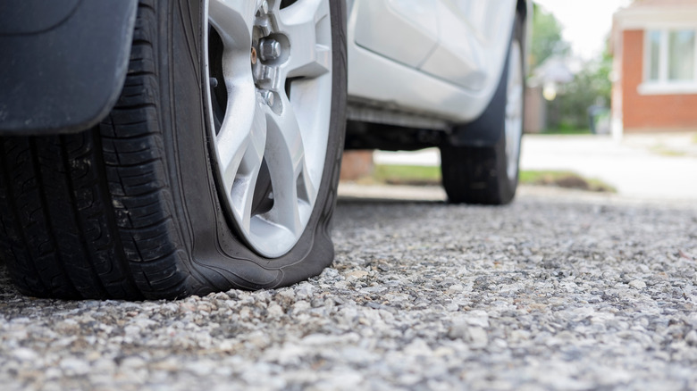 Car with deflated tire on gravel