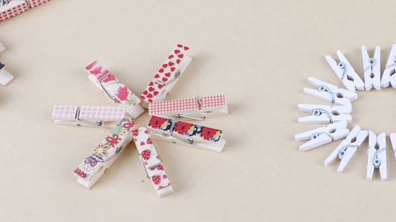 Patterned and white clothespins arranged in a star-shape and a ring on a table.