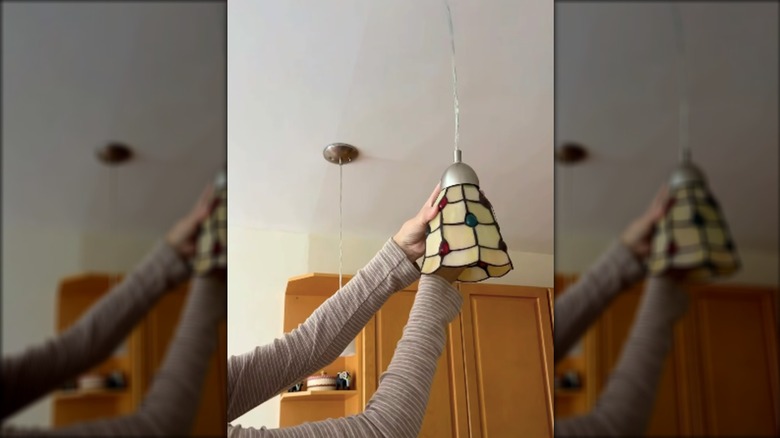woman changing pendant lampshade