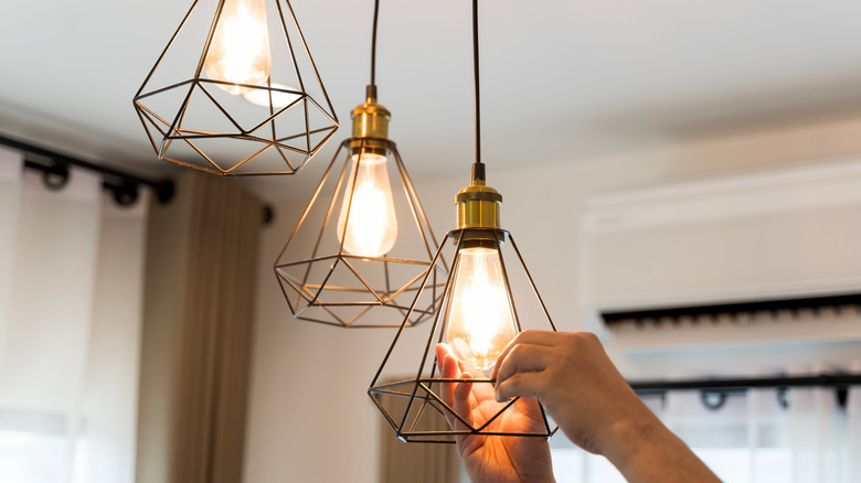 person changing lightbulb in pendant light
