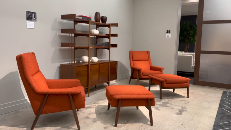 Red upholstered chairs and foot stools with a mid-century credenza in a showroom.