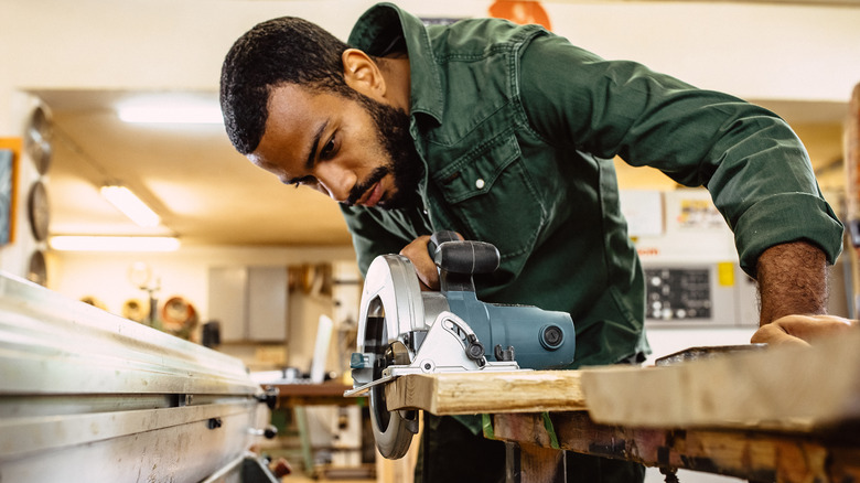 man cutting wood in workshop