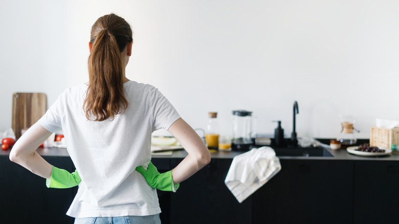 Woman observing messy kitchen counters