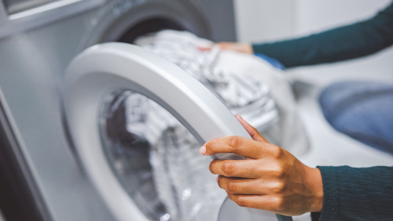 perosn putting clothes in washer 