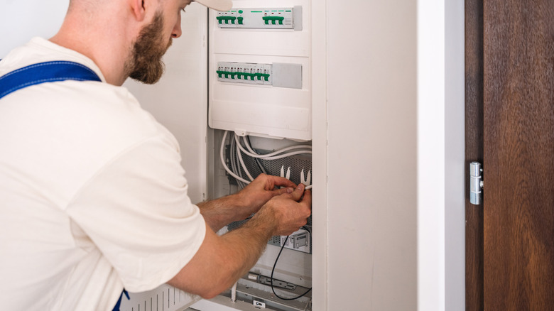 Man working on an electrical panel and holding wires