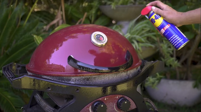 man spraying WD-40 on grill