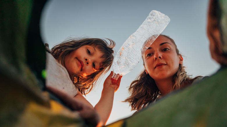 mother and daughter putting trash in can