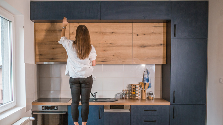 A woman looks at the cabinets in her kitchen