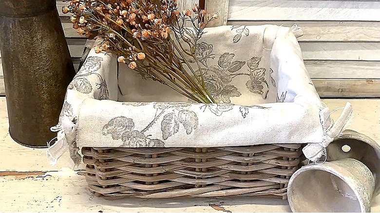 An IKEA basket with a fabric liner and artificial flowers inside