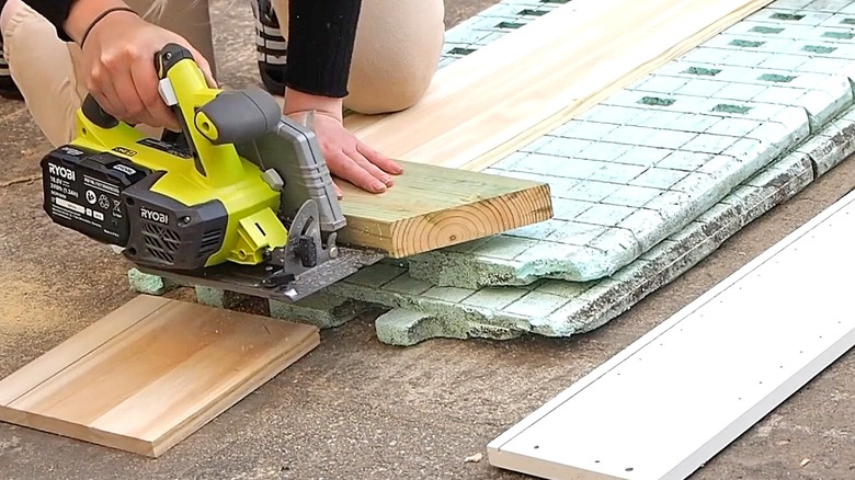 Close-up of a person using a saw to cut some boards outside