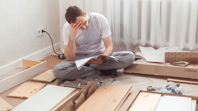 Stressed man assembling flat pack furniture