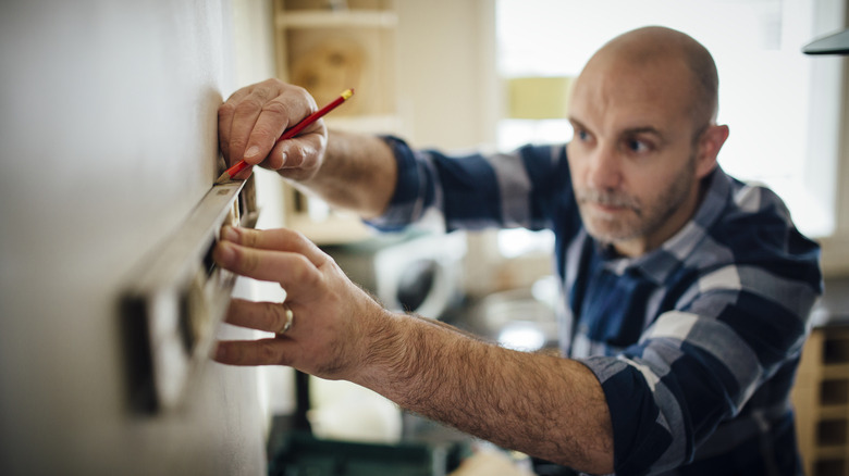 Person marking a place on the wall for a shelf