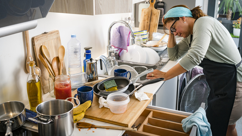 Stressed woman in messy kitchen