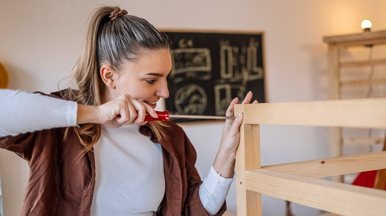 Woman assembling a piece of wooden furniture