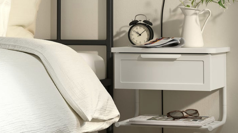 GRÅFJÄLLET bedside table in white with alarm clock, pitcher, and magazine on top