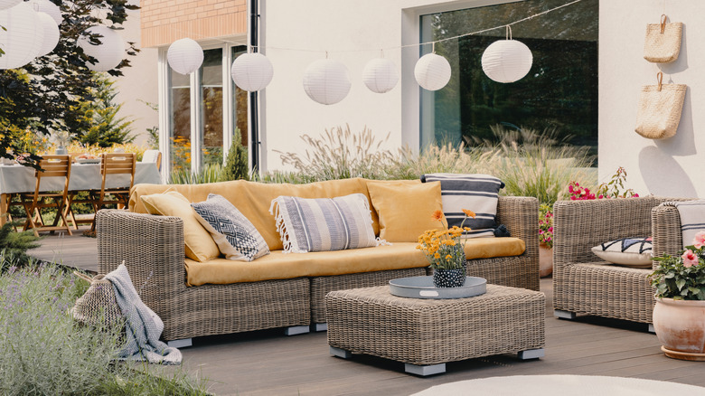 An outdoor seating area on a patio with hanging lamps, plants, and wall decor in the background