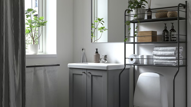 The FRÖSJÖN Over-the-toilet shelf with towels, toilet paper, and other items stored on it