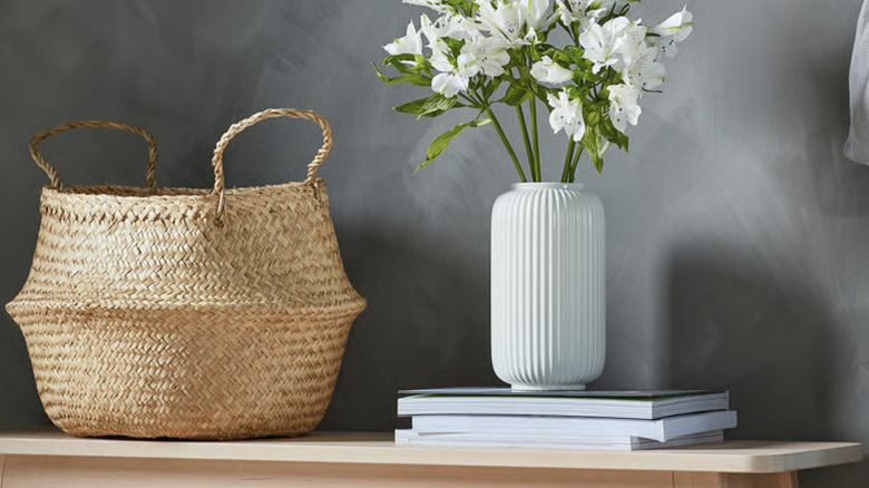 The IKEA FLÅDIS seagrass basket on a shelf near books and a vase of flowers