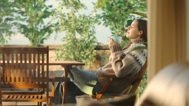 Woman sitting on patio drinking a cup of coffee