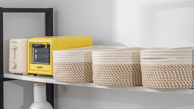 Neutral woven storage baskets are stored next to yellow and white kitchen appliances