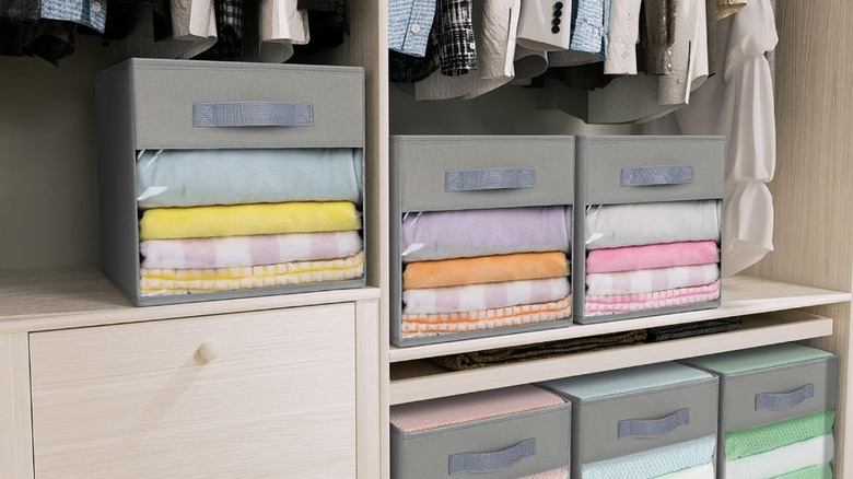 Grey storage cubes with transparent windows are stacked on a closet shelf.