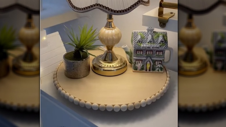 A SNUDDA lazy susan with wooden beads along the edge and decor pieces on top