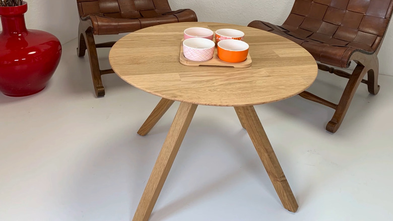 DIY table with angled legs and a lazy susan top with two brown chairs in the background