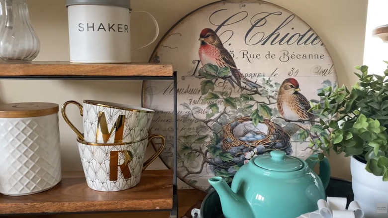 IKEA turntable decoupaged with a bird design leaning against the wall next to other decor pieces