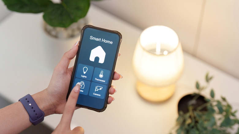Hands controlling a lit lamp using their smartphone
