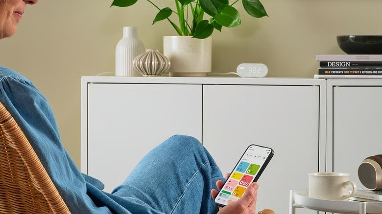 Woman controlling an air quality sensor placed on a desk
