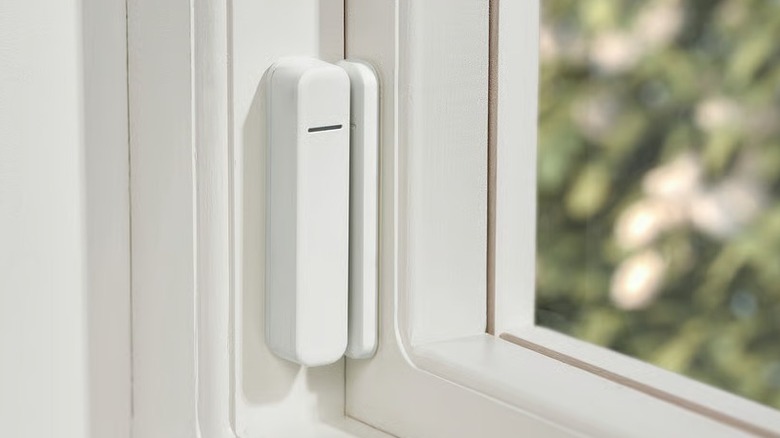 A small white sensor mounted on a window frame