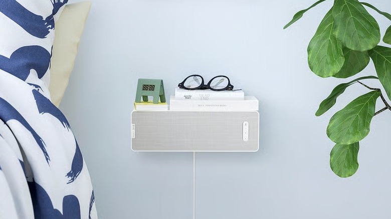 A speaker being used as a small floating shelf in a bedroom
