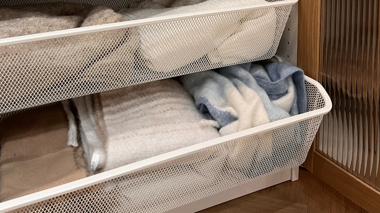 Baskets hold neatly folded blankets and clothes in pull-out drawers.