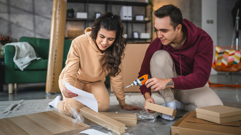 A young couple moving in new apartment, assembling furniture