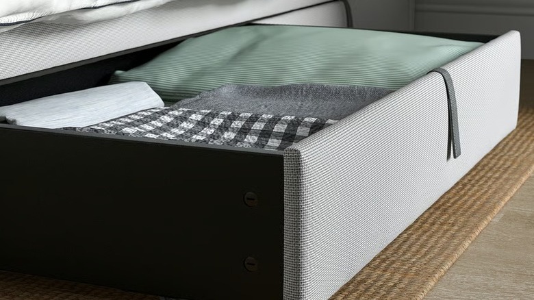 An underbed storage drawer filled with clothes